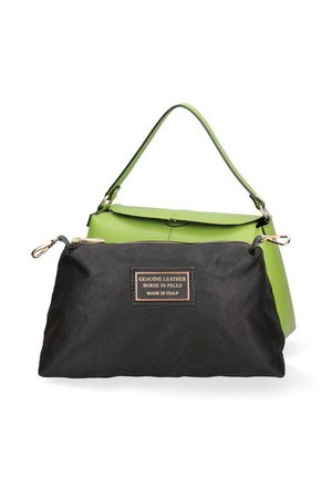 Kleine groene leren handtas met een afneembaar zwart tasje gelabeld als echt leer, gemaakt in Italië, tentoongesteld op een witte achtergrond.