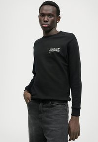 Μαύρη φούτερ μπλούζα από βαμβάκι με στρογγυλή λαιμόκοψη, που διαθέτει ένα μικρό λευκό λογότυπο "REPLAY RACING TEAM" στο στήθος και ριμπ μανίκια.