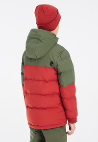 Giacca a vento imbottita rossa e verde con cappuccio, caratterizzata da un design trapuntato, polsini elasticizzati e un logo sulla schiena.