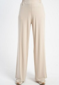 Jasne beżowe spodnie typu wide-leg, wykonane z gładkiego materiału, z elastycznym pasem w talii i bocznymi rozcięciami dla swobody ruchów.