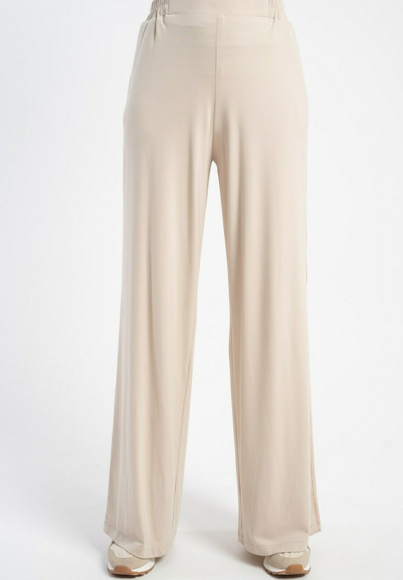Jasne beżowe spodnie typu wide-leg, wykonane z gładkiego materiału, z elastycznym pasem w talii i bocznymi rozcięciami dla swobody ruchów.