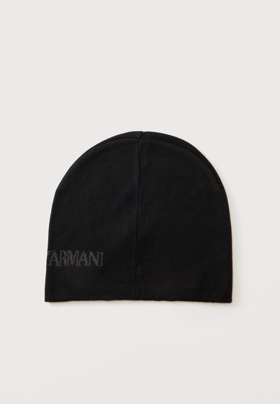 Черна плетена шапка тип бини с дискретен надпис на логото "Armani" близо до долния ръб на бял фон.
