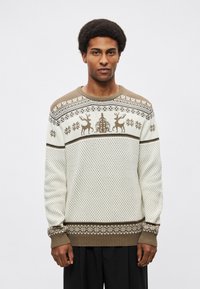 Λευκό πλεκτό πουλόβερ με καφέ γραφικό σχέδιο που περιλαμβάνει τάρανδους και νιφάδες χιονιού, με ριπ μανσέτες και τελείωμα, και στρογγυλή λαιμόκοψη.