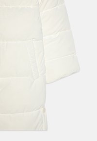 Vit pufferjacka med en strukturerad yta, horisontell sömnad och en sidoficka med tryckknappslås.