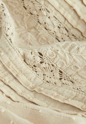 Linen fabric in soft beige with intricate lace detailing and textured stripes. Features delicate floral patterns and raised accents.