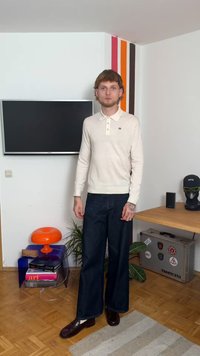 Κρεμ πόλο με μακριά μανίκια, γιακά και τρία κουμπιά, συνδυασμένο με σκούρους μπλε φαρδιούς τζιν και γυαλιστερά καστανά παπούτσια.