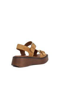 Suedine platform sandalen in bruin met een open ontwerp, verstelbare bandjes, accenten in goudkleurige gespen en een bruine textuurzool.