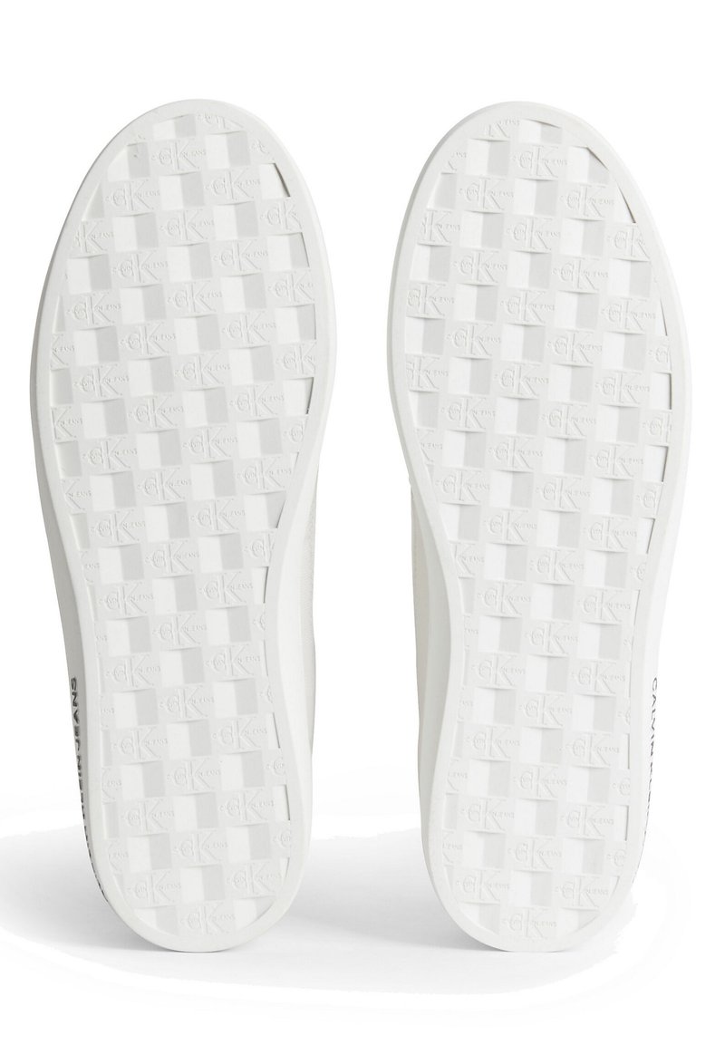 Suole di sneaker bianche con un motivo a griglia testurizzato, che presenta un marchio sottile e un design pulito e liscio.