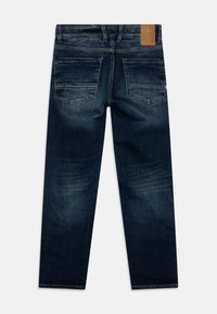 Granatowe dżinsy z prostymi nogawkami, z lewej strony z skórzaną łatą na pasku i dwiema tylnymi kieszeniami z detalami w szwie.