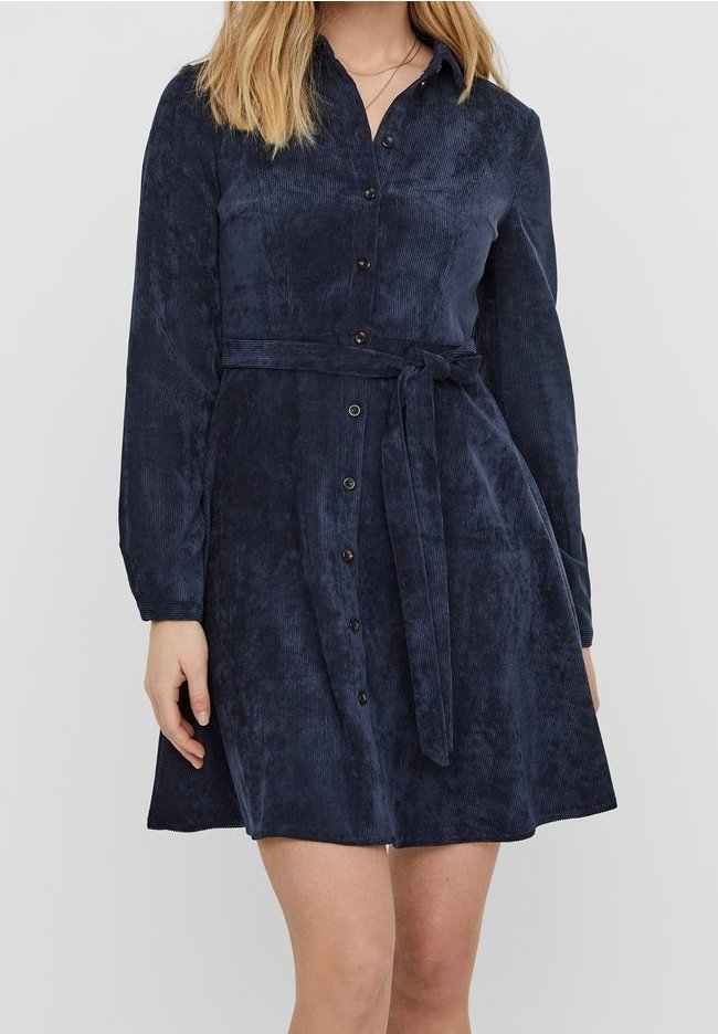 Robe en velours côtelé bleu marine avec des manches longues, fermeture à boutons sur le devant et ceinture en tissu assorti. Présente une texture lisse et une jupe évasée.