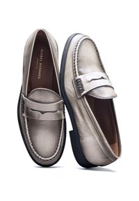 Light beige leather loafers with a rounded toe, stitched detailing, and a decorative strap across the vamps. Rubber outsole for grip.