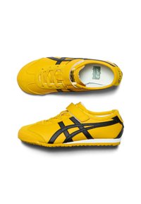 Gule sneaks med sorte accenter, der har en velcro-strop og snørebånd, struktureret gummi sål og glat syntetisk overmateriale.