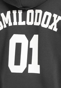 Felpa grigia scura con testo bianco che recita "SMILODOX" sopra il numero "01" in un font audace e squadrato. Texture di cotone morbido.