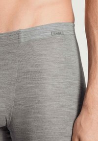 Leggings sportivi grigi in morbido tessuto testurizzato. Presentano un elastico in vita con una piccola etichetta con il logo "CALIDA". Design aderente.