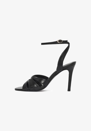Black high-heeled sandal with thin ankle strap and buckle, featuring crisscross straps over open toe and stiletto heel.