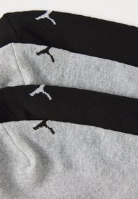 Trois paires de chaussettes présentant un mélange de matières grises et noires, avec un tissu texturé et un accent de logo en blanc.
