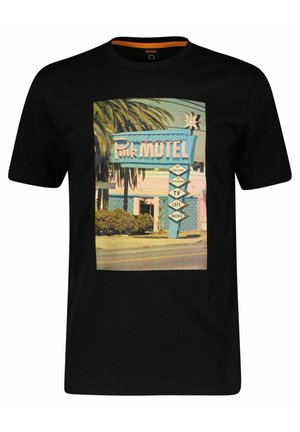 Schwarzes T-Shirt mit einem Vintage-Druck eines pinkfarbenen Motelschilds mit Palmen, Schriftzug und Richtungspfeilen, hergestellt aus weichem Baumwollmaterial.