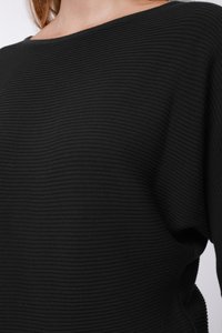 Juodas ribuotas megztinis su plačiu valtinėliu kaklu, pagamintas iš tekstūruotos medžiagos. Dizainas akcentuoja horizontalias juostas ir laisvą siluetą.