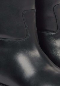 Czarne skórzane botki ze gładką fakturą i elastycznymi panelami po bokach, z subtelnymi przeszyciami i zaokrąglonym noskiem.