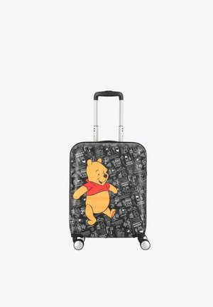 Valise rigide noire avec un grand graphique coloré de Winnie l'Ourson portant une chemise rouge, dotée de quatre roues et d'une poignée télescopique.