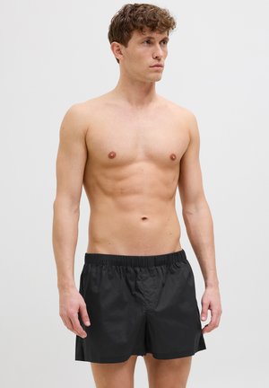 Schwarze Badeshorts aus leichtem, glattem Stoff mit einem elastischen Bund. Bietet eine lockere Passform und ein einfaches, klassisches Design.