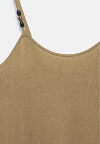 Close-up of beige knitted tank top strap with three decorative beads, two black and one brown, on the left side.