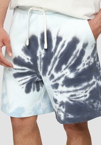 Shorts tie-dye bleu clair et gris avec une taille élastique et un cordon de serrage, des poches latérales et un tissu doux et texturé.