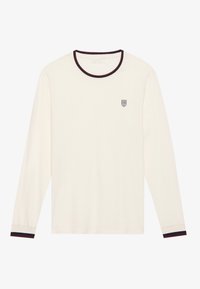 Camisa de manga larga color crema con cuello redondo. Presenta un ribete a rayas en color rojo oscuro y azul marino en el cuello y los puños. Pequeño logo en el pecho.