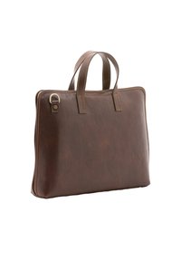 Mallette en cuir marron avec doubles poignées, coutures visibles et anneau métallique dans le coin supérieur gauche, présentée sur un fond blanc.