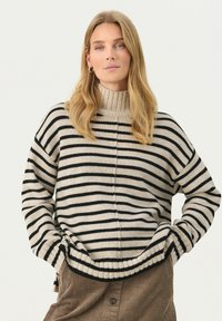 Gestreifter Pullover mit hohem, geripptem Kragen, der schwarze und cremige horizontale Streifen aufweist. Weicher Stoff und lockere Passform.
