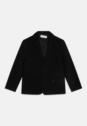 Blazer noir en tissu lisse, avec un revers cranté, deux poches avant, une fermeture à bouton unique et un logo brodé subtil.