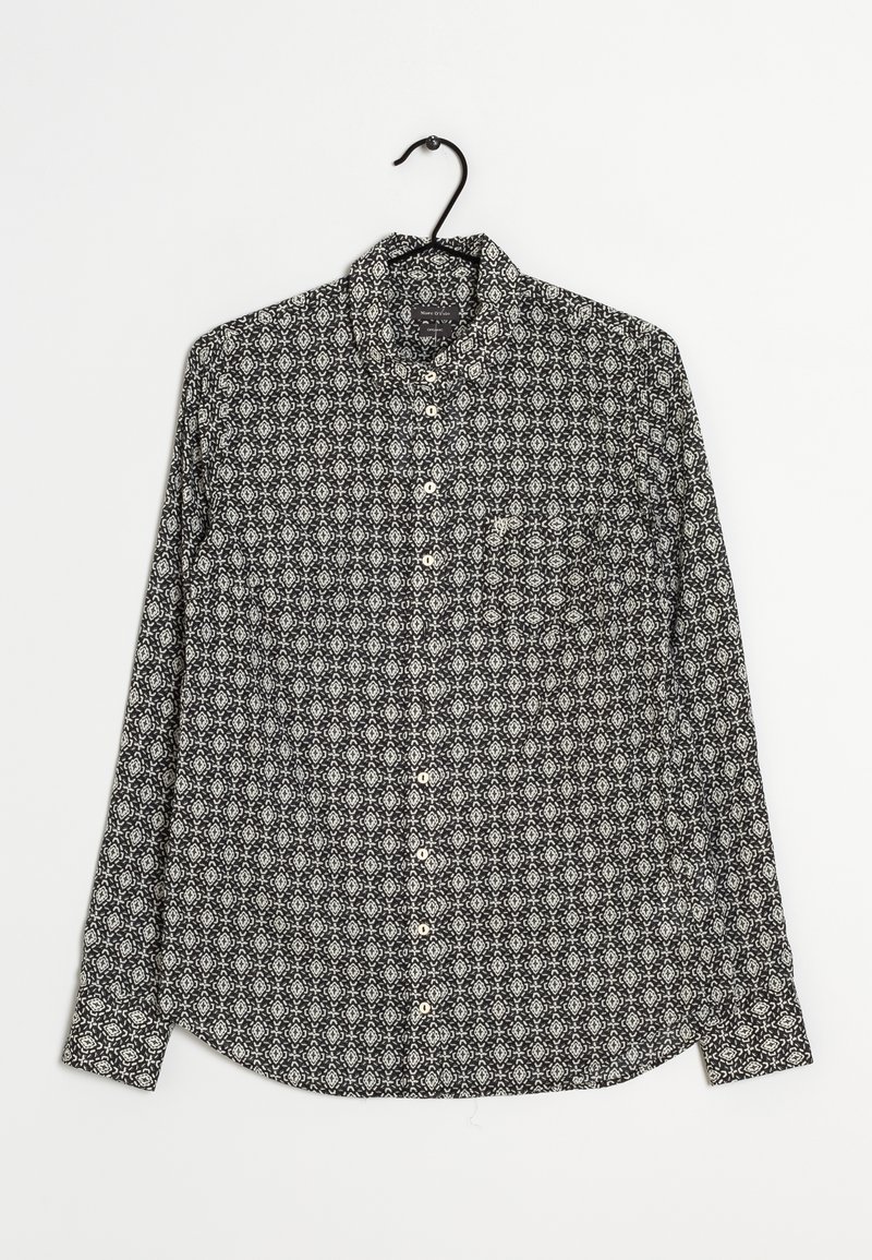 Chemise à manches longues en noir et blanc présentant des motifs géométriques complexes, un col boutonné et une poche poitrine. Tissu en coton, texture lisse.