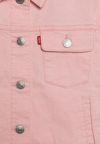 Giubbotto in denim rosa chiaro con bottoni a pressione argentati, una tasca sul petto e un dettaglio in rosso sul lato sinistro. Texture liscia.