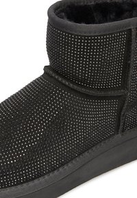 Stivali alla caviglia neri in suede testurizzato, impreziositi da piccole pietre nere, con un interno morbido e una suola in gomma resistente.