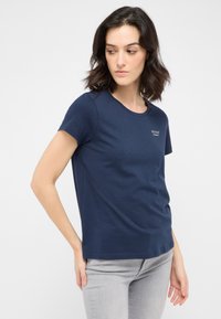 Marineblaue Baumwoll-T-Shirt mit kurzen Ärmeln, rundem Halsausschnitt und kleinem Logo auf der Brust. Glatte Textur und taillierter Schnitt.