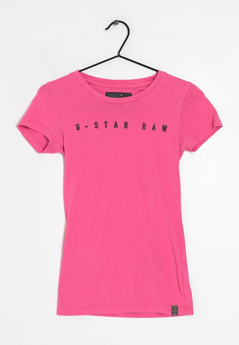 Růžové bavlněné tričko s krátkým rukávem, se zaobleným výstřihem a černým textem "G-STAR RAW" tištěným na přední straně. Viditelný štítek velikost S.