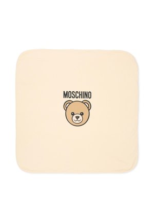 Cuscino quadrato beige con angoli arrotondati che presenta al centro il volto di un orsetto dei cartoni animati e la parola "MOSCHINO" sopra.