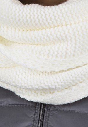 Écharpe infinity blanche, épaisse et tricotée, enroulée autour du cou par-dessus une veste zippée gris foncé.