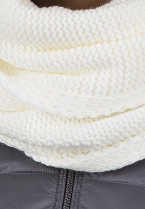 Écharpe infinity blanche, épaisse et tricotée, enroulée autour du cou par-dessus une veste zippée gris foncé.