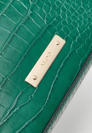 Groene nepkrokodillenleren tassenafdeling met een rechthoekige gouden merkplaat van ALDO, bevestigd met twee schroeven.