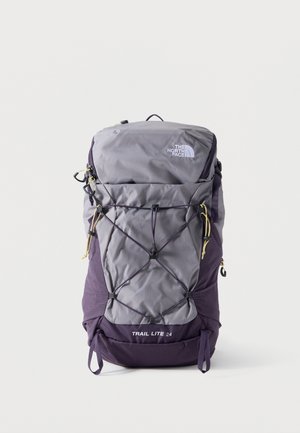 Grijze en paarse North Face Trail Lite 24 rugzak met elastisch koord aan de voorkant en meerdere ritszakken, rechtopstaand op een witte achtergrond.