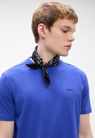 T-shirt en coton bleu avec un col rond, arborant un petit logo 'BOSS' noir. Complété par un bandana noir à motif noué autour du cou.