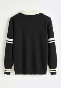 Pull noir avec col côtelé blanc, bande blanche et double bande noire sur les manches, et poignets à rayures blanches et noires, vu de dos.