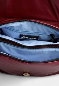 Bordeaux handtas met een glanzende afwerking, voorzien van een blauwe binnenkant, dubbele compartimenten, een zwarte rits en een ronde gouden knoopsluiting.