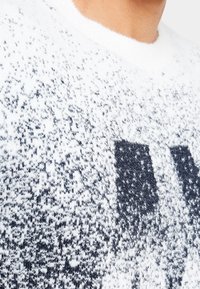 Vit tröja med en fluffig textur som har en grå gradient och stora svarta bokstäver. Rundad halsringning, mjukt material och avslappnad design.