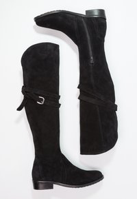 Botas negras por encima de la rodilla hechas de ante, con cremallera lateral, acento de hebilla y un tacón bajo y texturizado. Diseño limpio y minimalista.