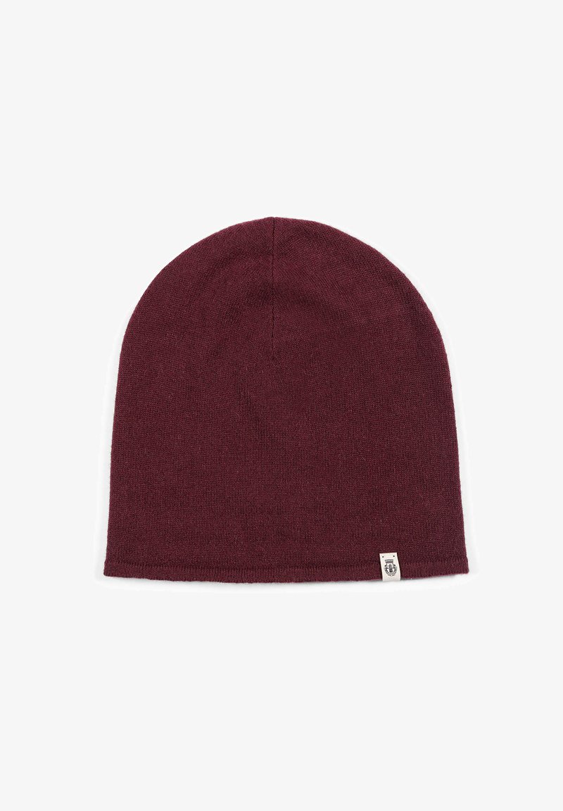 Maroon knitted beanie hat with small beige label on bottom edge, displayed flat on white background.