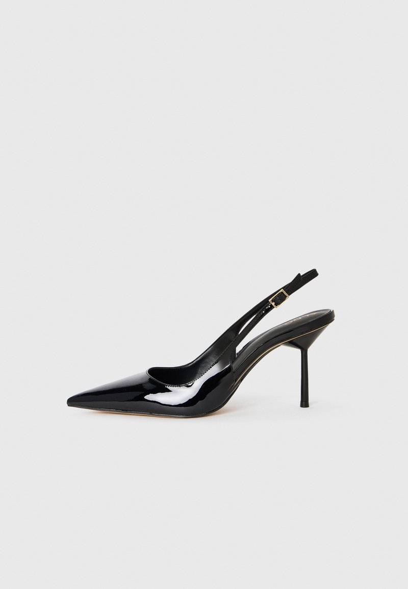 Scarpa slingback con tacco a stiletto in vernice nera, punta affusolata, dotata di una sottile fascia e una fibbia dorata, su sfondo bianco.