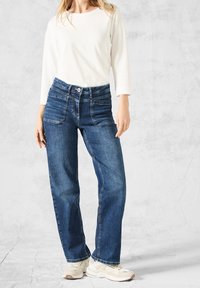 Lätt vikt långärmad vit skjorta som matchas med mörkblå denimjeans med rak passform, fem fickor och knappstängning.