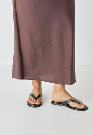 Sorte flip-flopsandaler med en struktureret, blank overflade; V-formede remme; kombineret med en lang, flydende brun nederdel.